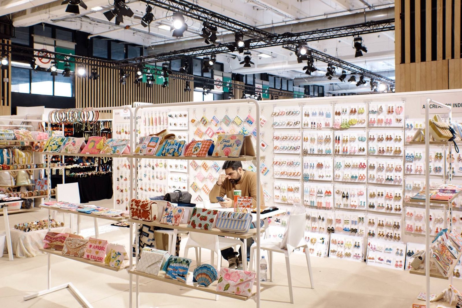 An Indian exhibitor's accessories stand at a Paris fashion trade show, walls of earrings and beaded bags.