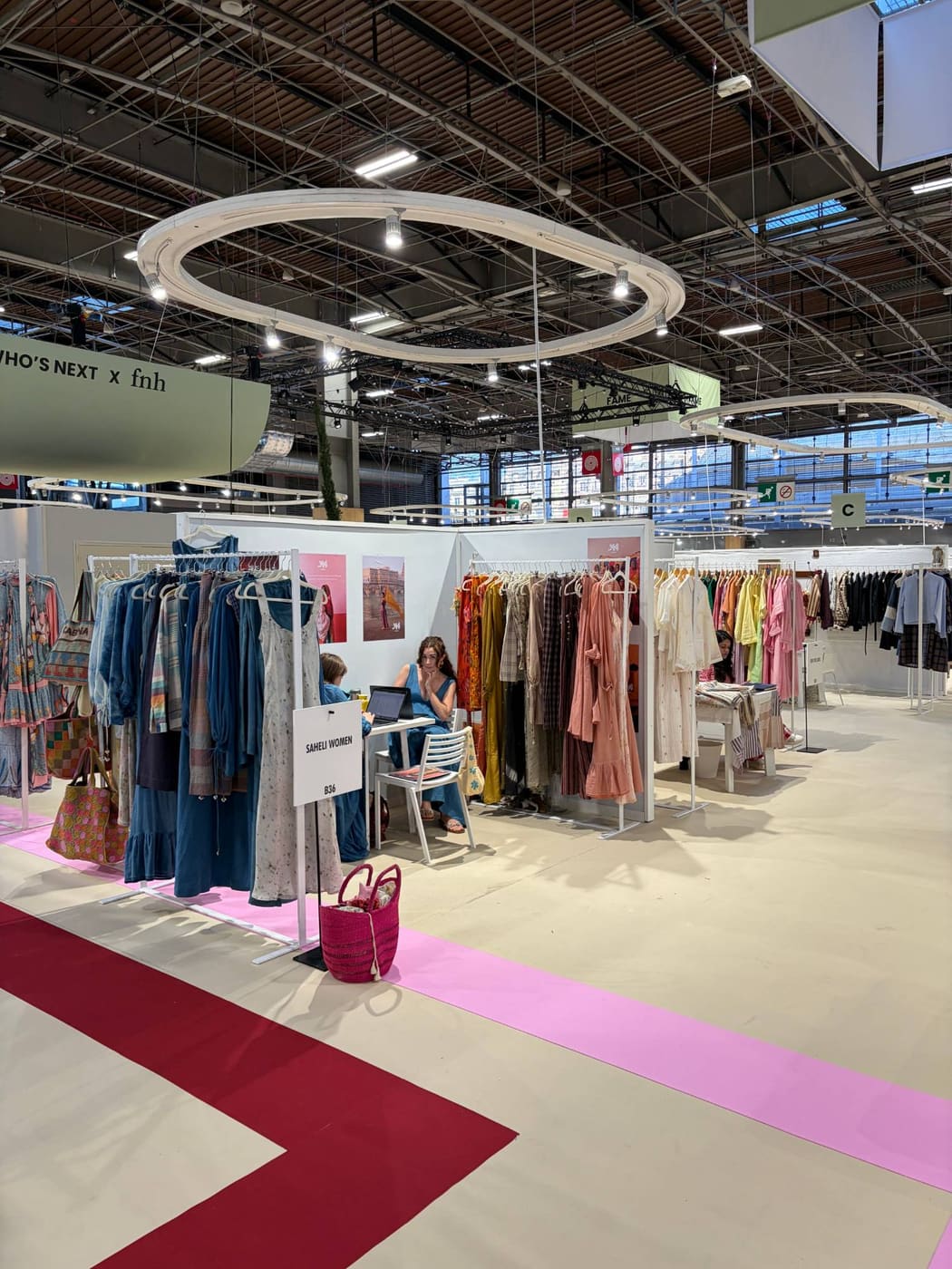 Aisle at Who's Next September 2026 with sector signs overhead and the Saheli Women stand, B36, in the foreground.