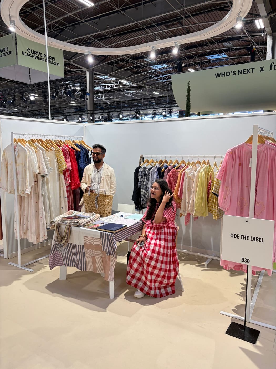The Ode the Label team at stand B30, Who's Next September 2026, with rails of hand-embroidered cotton shirts and dresses.