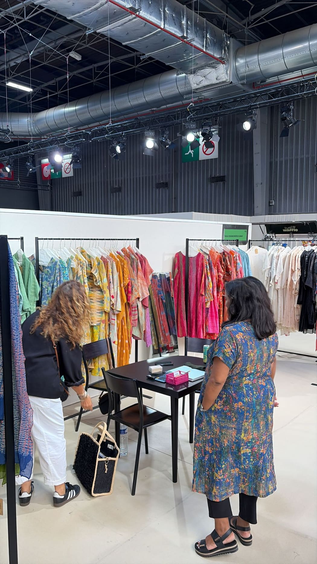 A buyer looking at hand-dyed dresses with the team of Raga Designs by Neeru Kumar at Who's Next Paris, September 2026.